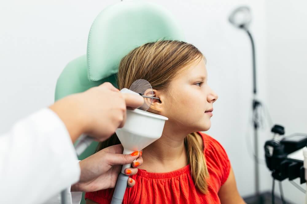 All About Hearing doctor cleaning a little girl's ear